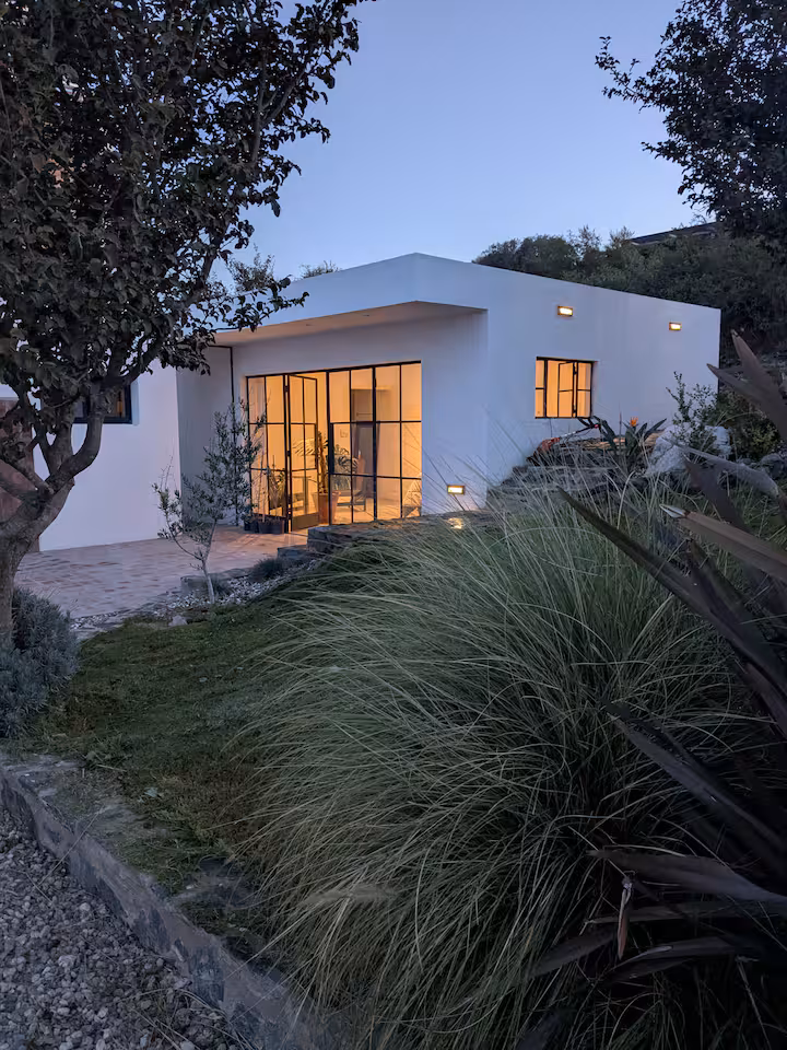 Quinta Sierras at dusk — steel-frame windows glowing over the valley
